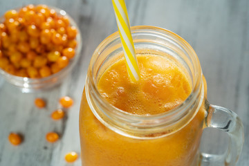 Fresh organic yellow smoothie in glass mug on white wooden table, close up. Refreshing summer fruit drink. The concept of healthy eating. Sea buckthorn smoothie