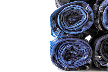 Jeans stacked on white background. Stack of various shades of blue jeans on white background.