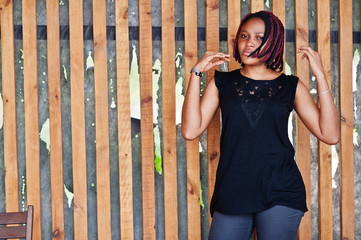 Young african american woman posed against wooden wall.