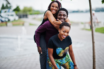 Fototapeta na wymiar Three african american friends having fun together. Jump on shoulder.