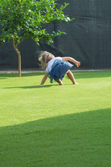 Niña rubia jugando en el césped / Little blonde girl playing on the grass