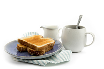 Obraz na płótnie Canvas two slices of white bread toast a blue plate with a coffee cup on a green napkin isolated on white