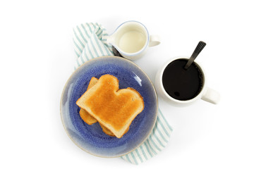 overhead view of two slices of white bread toast a blue plate with a coffee cup on a green napkin isolated on white