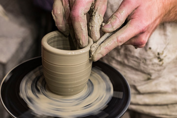 Fototapeta na wymiar Hands of a potter make a handmade mug out of clay photo taken close-up