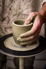 Hands of a potter make a handmade mug out of clay photo taken close-up