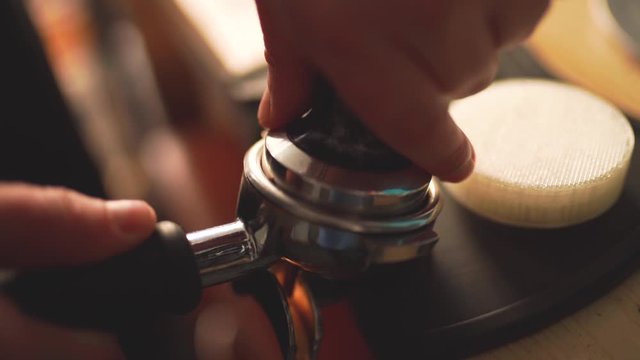 Slow motion of the process of making coffee step by step. Barista hands tamping freshly ground coffee beans 