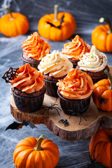 Halloween cupcakes and pumpkins on dark web background. Sweets for holiday party.