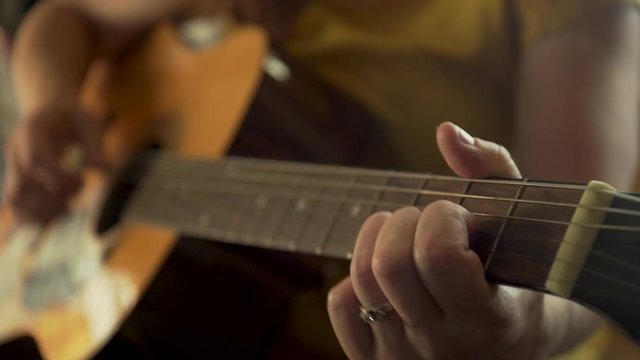 Woman's fingers play across the fretboard of a guitar