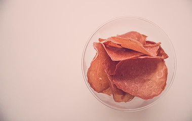 Meat crispy chips in a clear glass. Snacks to beer from dried meat in a glass bowl.
