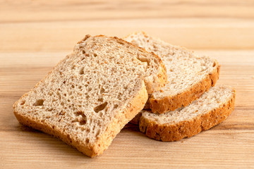 Three slices of whole wheat toast bread isolated on light wood.