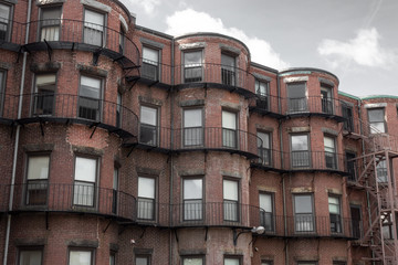 Fototapeta na wymiar Run down brownstone apartments viewed from the rear before gray sky, horizontal aspect