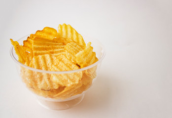 Potato chips in a clear glass. Yellow grooved potato chips in a glass bowl.