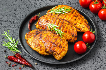 Grilled buffalo chicken breasts, cast iron skillet, dark background.