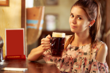 young woman in front of a bar in a cafe with a beer
