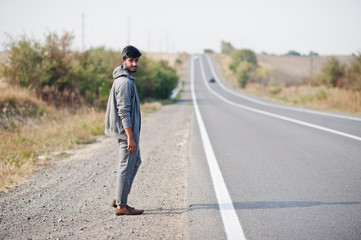 Fototapeta na wymiar Hitchhiking indian man travelling by hitchhike on road side on highway.