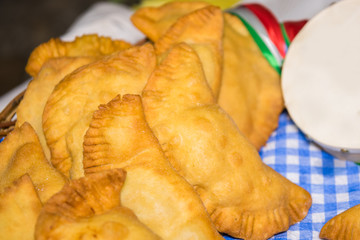 Puglia food: fried pies called panzerotti in a basket, made with tomato sauce, mozzarella and prosciutto, close-up with tambourine of Salento