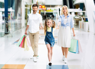 Family Walking In Shopping Mall Smiling At Camera
