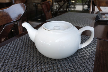 White porcelain teapot on a table in a cafe