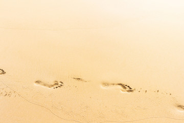 Fototapeta na wymiar Footprints in the yellow sand, tropical sandy beach background