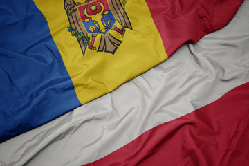 waving colorful flag of poland and national flag of moldova.