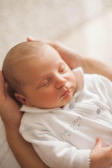 Cute newborn baby sleeping in mother's arms. Motherhood.