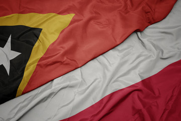 waving colorful flag of poland and national flag of east timor.