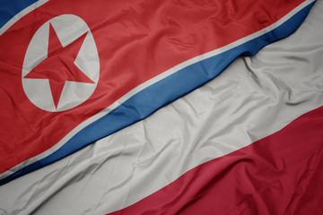 waving colorful flag of poland and national flag of north korea.