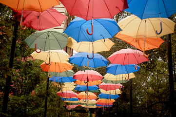 Fototapeta na wymiar Texture. Lots of umbrellas hanging against the sky. Protection from sun and rain. Red, orange and blue.