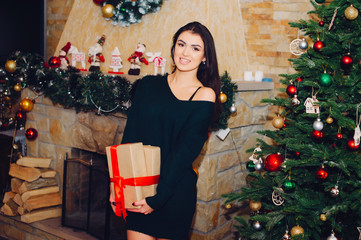 Beautiful girl in a decorated room. Woman near Christmas tree. Lady in a sweaters