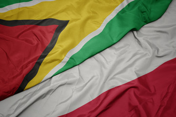 waving colorful flag of poland and national flag of guyana.