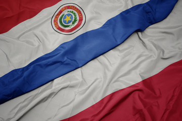 Fototapeta premium waving colorful flag of poland and national flag of paraguay.