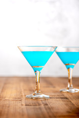 Blue cocktail in glasses on a wooden tabletop, gray background. Cocktails with blue curacao closeup, copy space