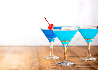 Blue cocktail in glasses on a wooden tabletop, gray background. Cocktails with blue curacao closeup, copy space
