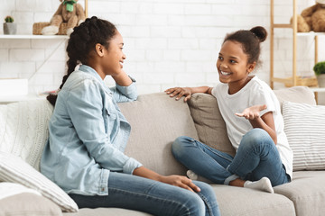 Two lovely black sisters having conversation at home