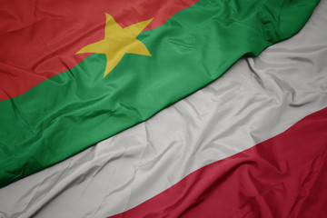 waving colorful flag of poland and national flag of burkina faso.