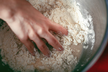 Woman kneads dough in bowl, close up
