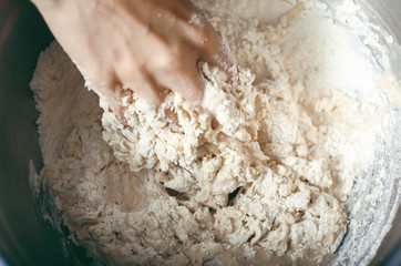 Woman kneads dough in bowl, close up