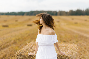 A girl in a white dress and with long hair turns her head, the hair develops on her face, the girl in the field