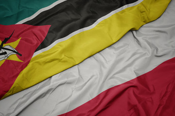waving colorful flag of poland and national flag of mozambique.