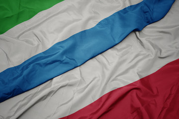 waving colorful flag of poland and national flag of sierra leone.