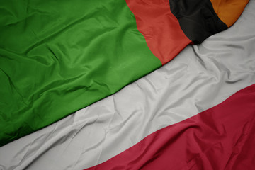 waving colorful flag of poland and national flag of zambia.