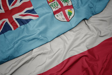 Naklejka premium waving colorful flag of poland and national flag of Fiji .