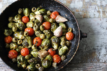 Baked Brussels sprouts in a pan with cherry tomatoes, garlic and olives. Vegan food. Diet concept. Autumn food.