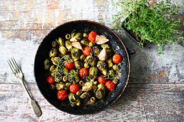 Baked Brussels sprouts in a pan with cherry tomatoes, garlic and olives. Vegan food. Diet concept. Autumn food.