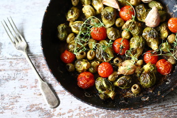 Baked Brussels sprouts in a pan with cherry tomatoes, garlic and olives. Vegan food. Diet concept. Autumn food.