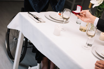 cropped view of man making wedding proposal to disabled girlfriend during romantic dinner