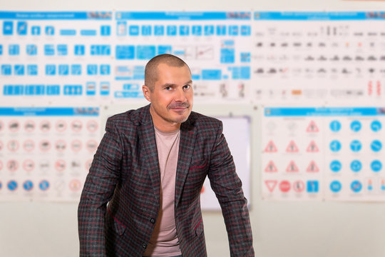 male driving instructor on blurred background of the training room with traffic signs