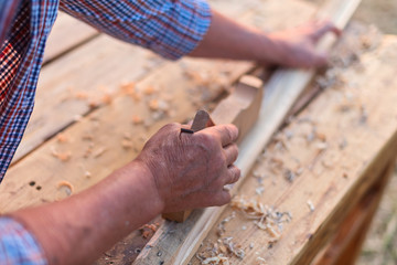 Hand of old carpenter male works on wood