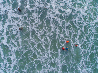 Aerial view of bubbles from waves and people enjoying their time at the beach.