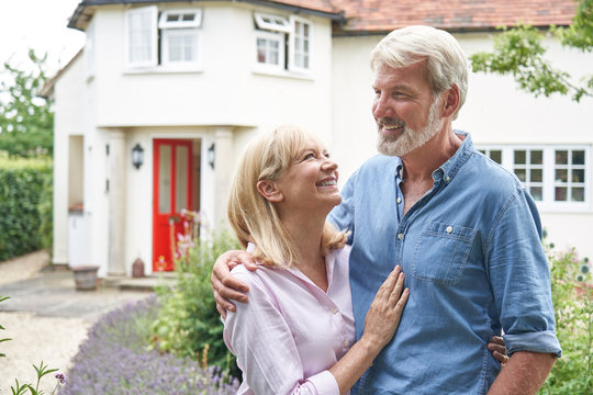 Mature Couple Standing In Garden In Front Of Dream Home In Countryside